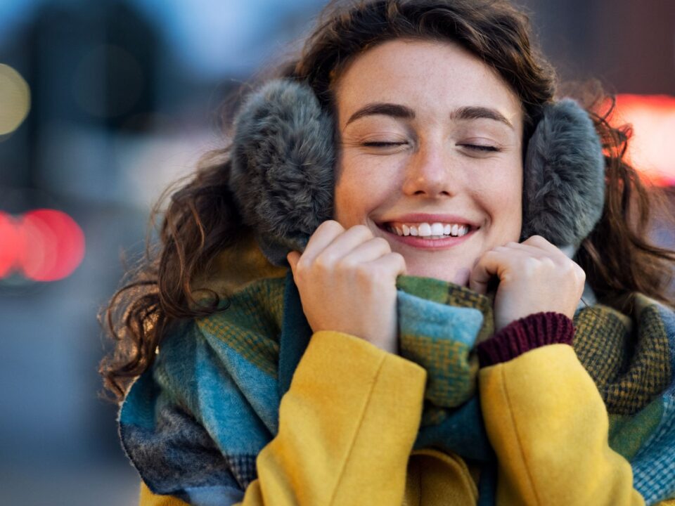 ragazza che sorride al freddo con scaldaorecchie